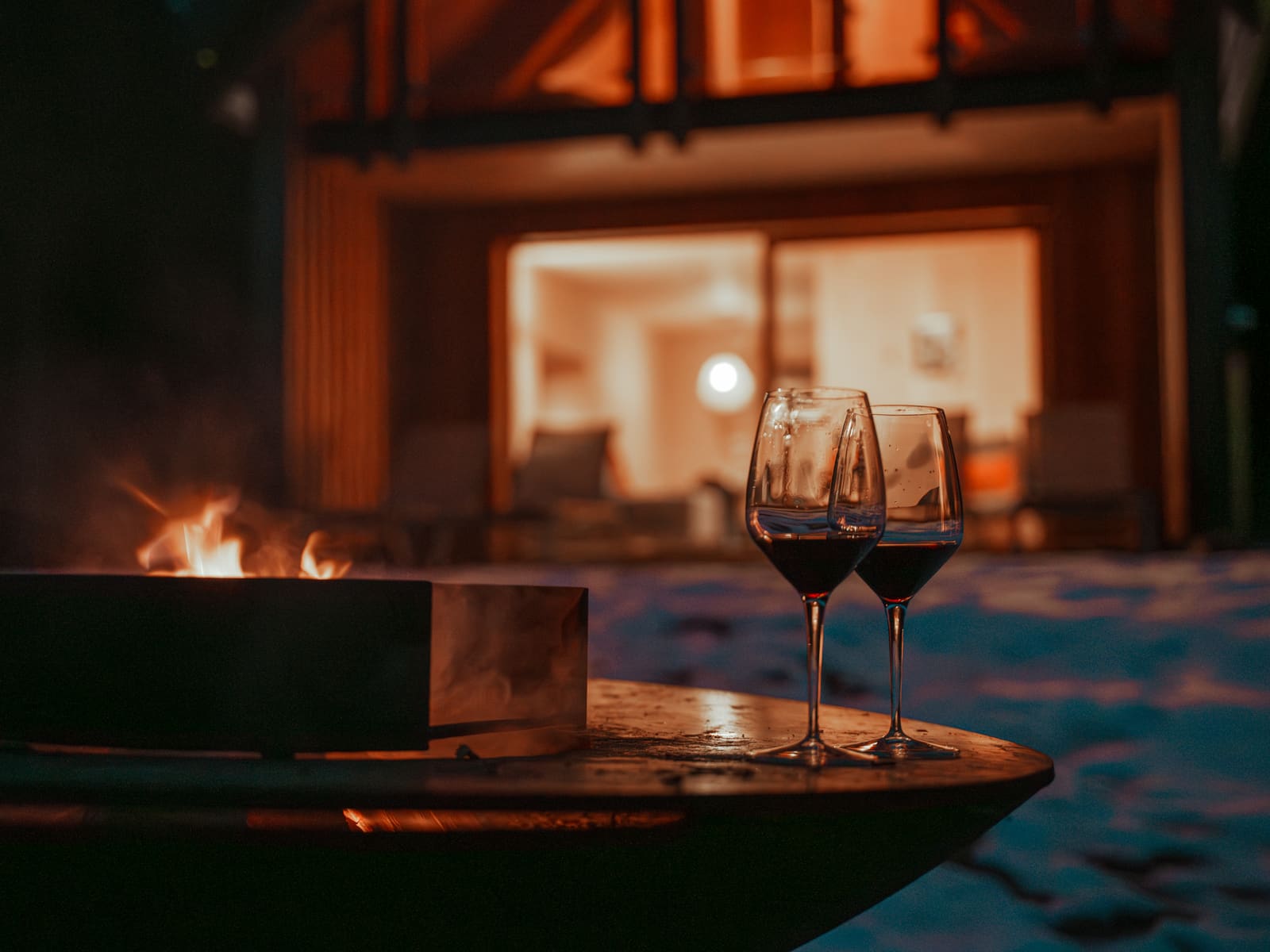 Feuerschale und Weingläser vor dem Chalet am Abend