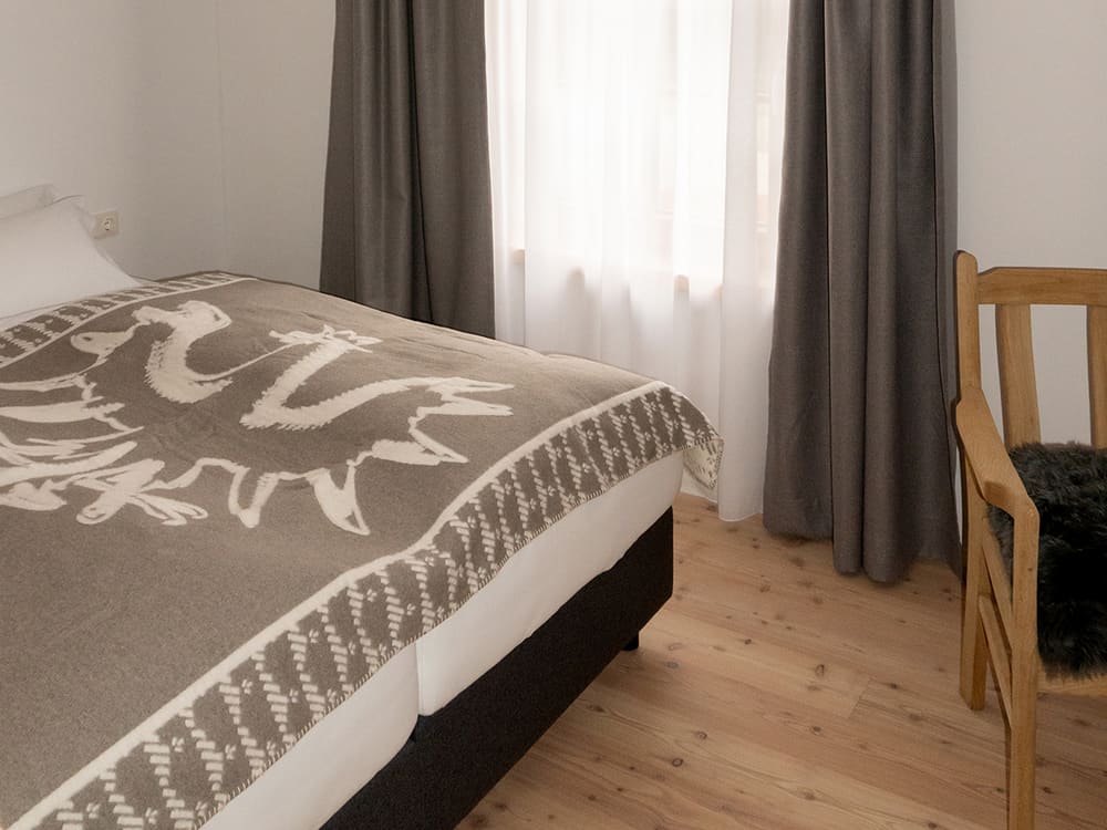 Doppelbett mit Wolldecke und Holzstuhl