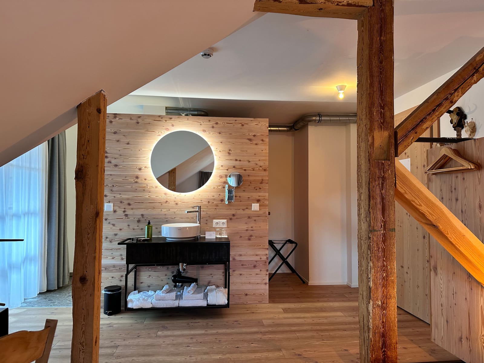 Waschtisch vor der Holzwand mit rundem Spiegel